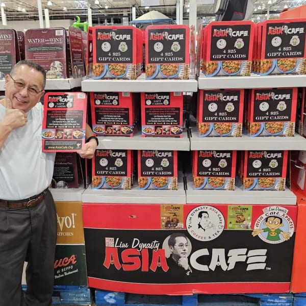 A man gives a thumbs-up next to a large display of Lim Dynasty Asia Cafe gift cards.
