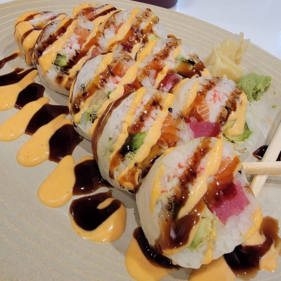 A plate of Lim Dynasty sushi rolls with various fillings, drizzled with spicy mayo and eel sauce.