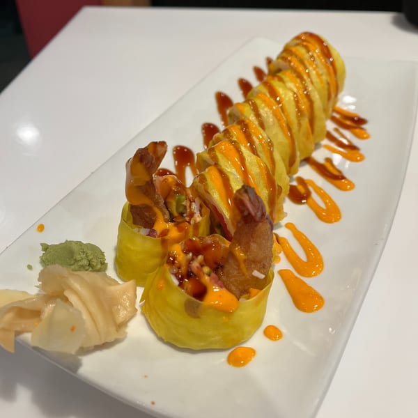 Lim Dynasty Asia Cafe & Xpress's sushi roll with shrimp tempura, drizzled with orange and brown sauces.